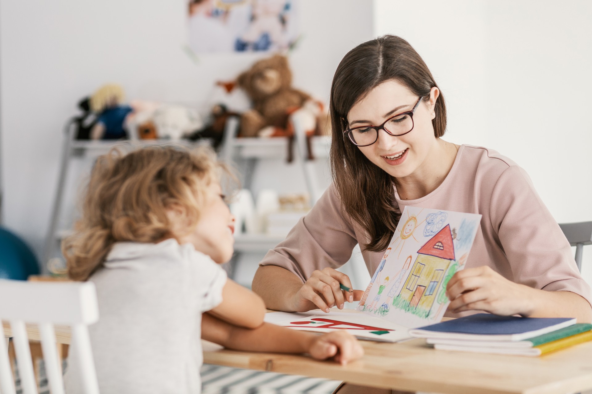 A professional child education therapist having a meeting with a kid in a family support center.